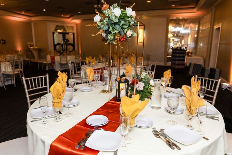 Reception table with tall floral centerpiece and burnt orange runner