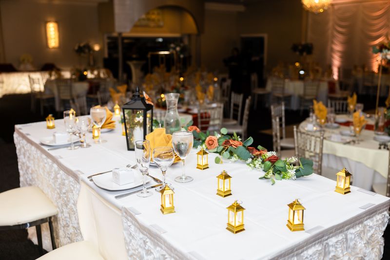 Head table styled with gold lanterns and greenery