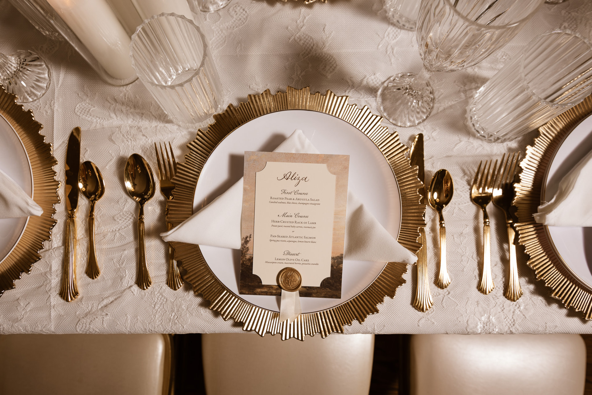 Close-up of a gold charger, wax-sealed menu, and gold flatware