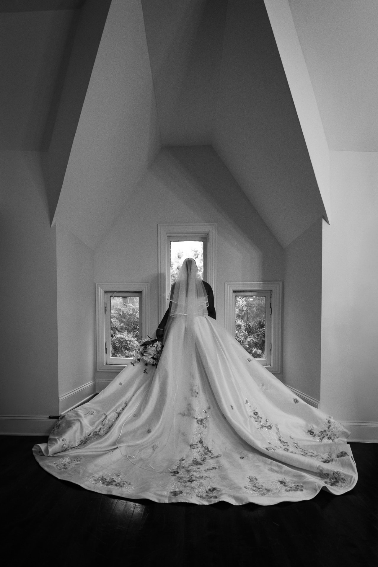 Bride by the window with a full embroidered train, black and white