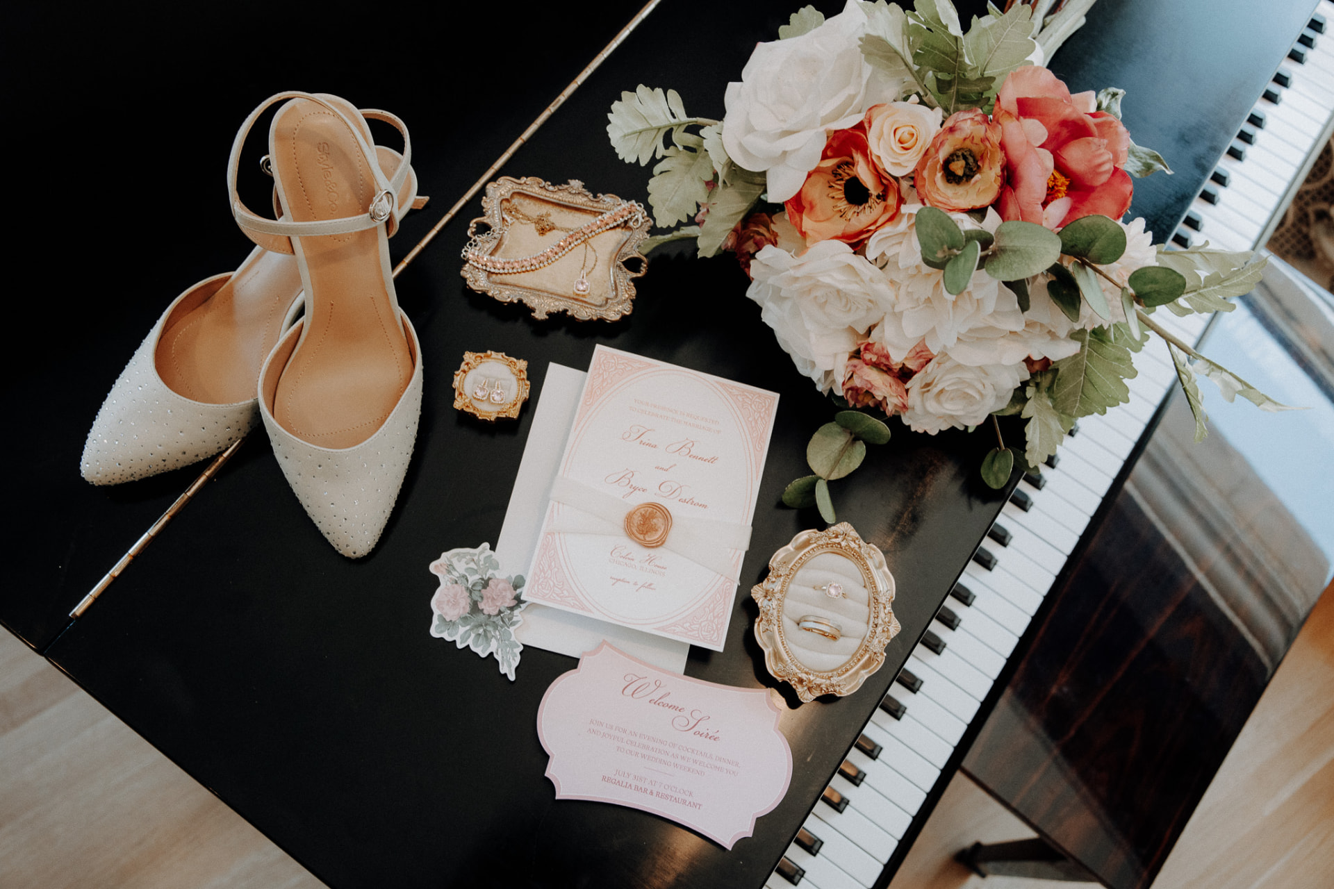Bridal details flatlay with heels, rings, and invitation suite on a grand piano