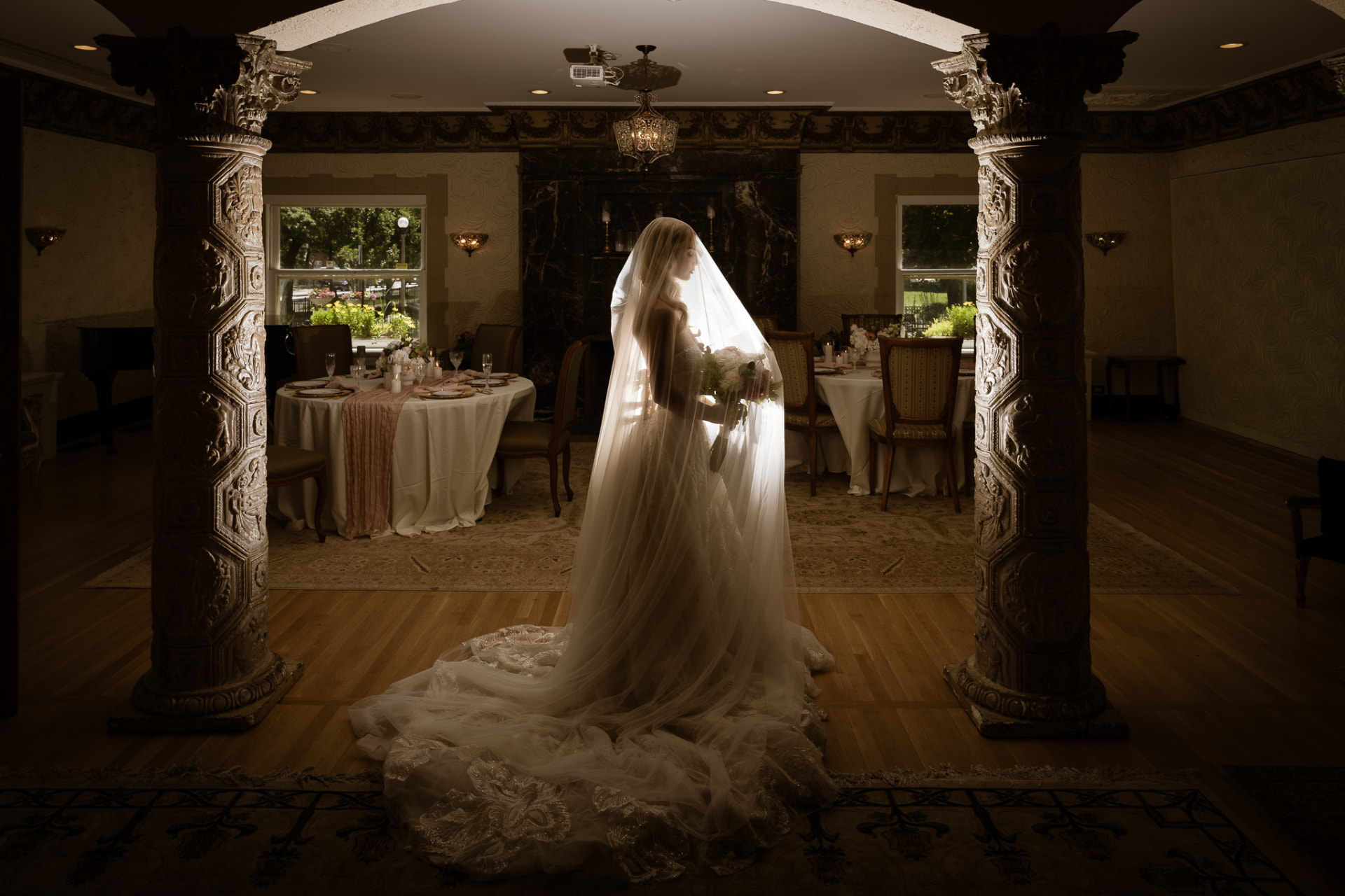 Veiled bride framed by carved columns in the reception room