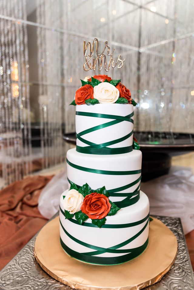 Three-tier wedding cake with green ribbon and roses