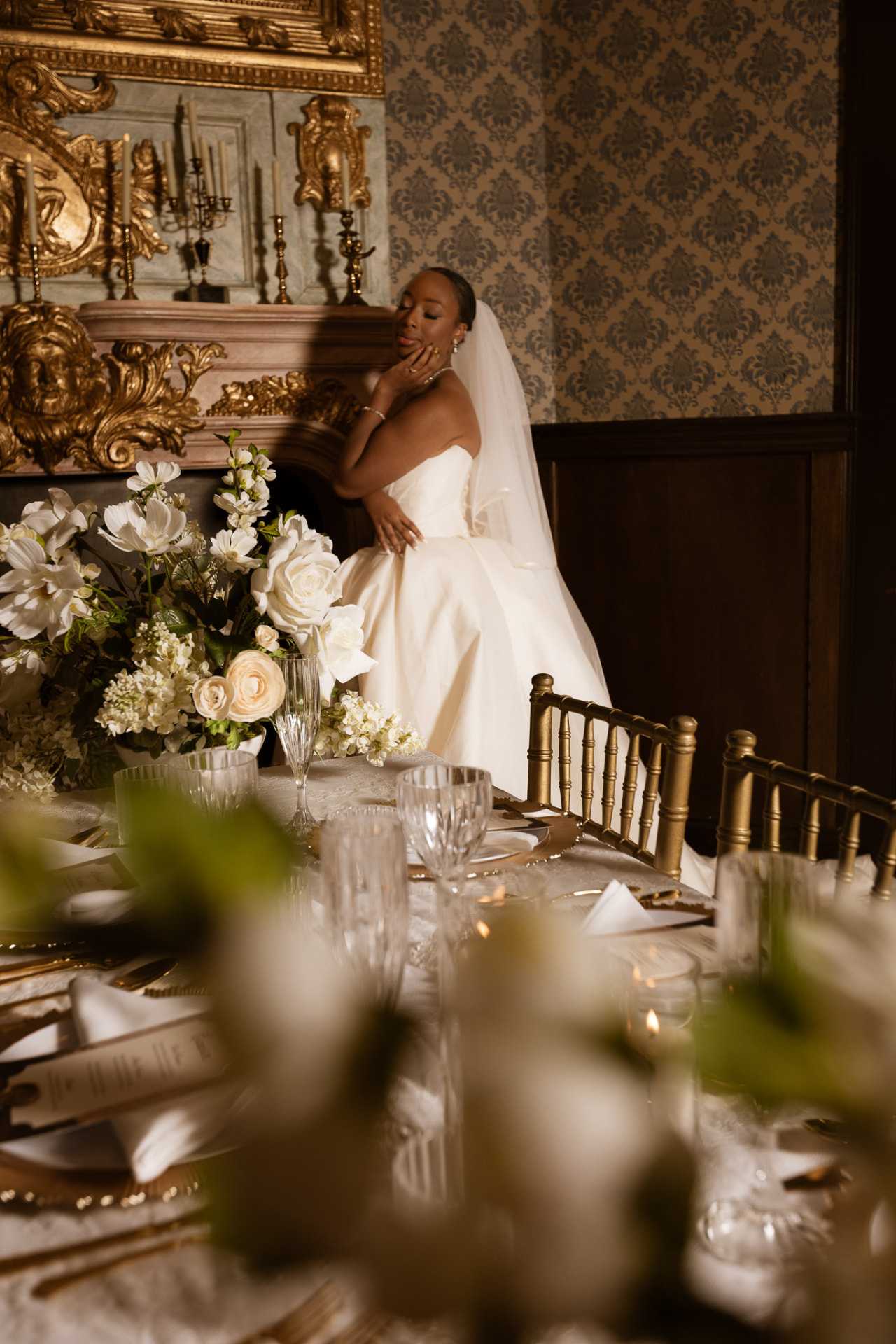 Bride seated by the gilded mantel beside the styled table