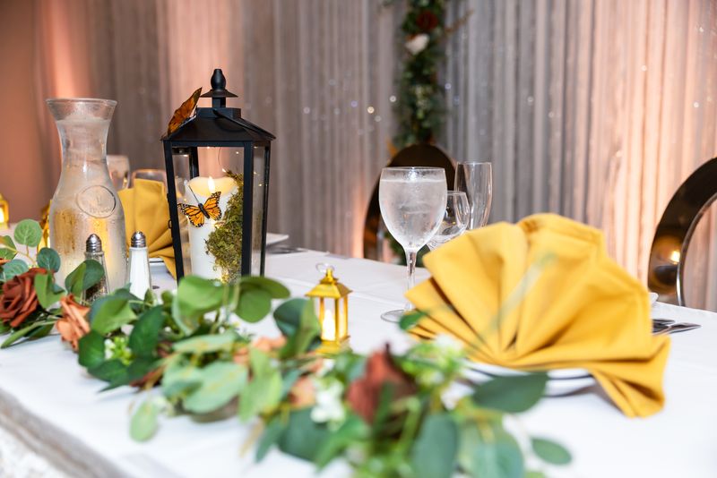 Lantern centerpiece with yellow napkins and greenery